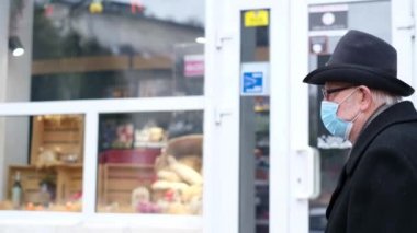 Yüzünde maske olan koruyucu maskeli bir emekli sokakta yürür.