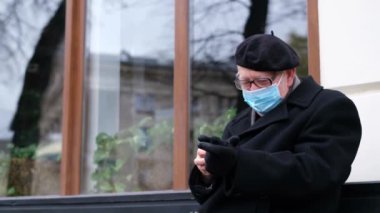 Emekli adam bir bankta oturuyor, eldiven giyiyor, soğuk bir sonbahar günü..