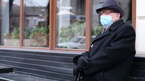 Le pensionné est assis sur un banc, il est dans un masque de protection, protection contre les virus, — Video