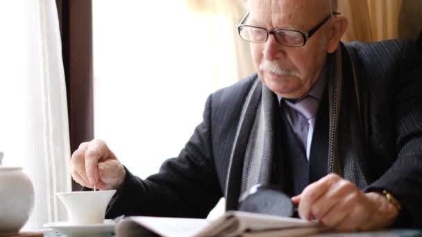 Portrét starého šedovlasého dědečka s brýlemi v elegantním oblečení, čte noviny — Stock video