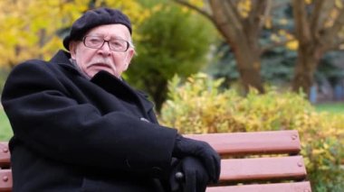 Yaşlı İtalyan parkta dinleniyor, sarı yapraklara bakıyor. Emeklilik hayatı 