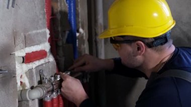 Erkek bir tesisatçı evdeki su borularını kontrol ediyor, işçi elleri ısıtma sistemini tamir ediyor.