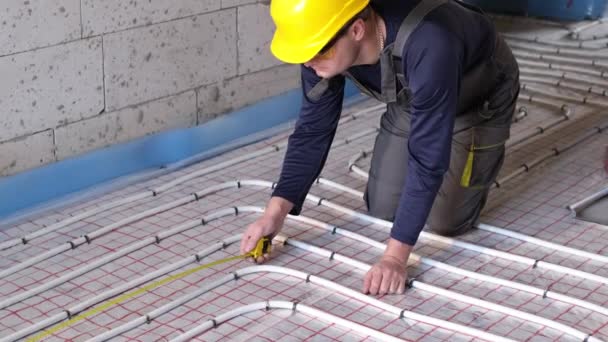 Le travailleur pose des tuyaux pour un plancher isolé thermiquement — Video