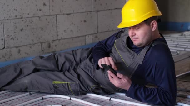 L'idraulico si riposa dopo il lavoro. tiene in mano uno smartphone. — Video Stock