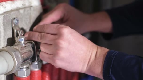 Чоловік-сантехнік перевіряє труби водопостачання в будинку, робочі руки фіксують систему опалення — стокове відео