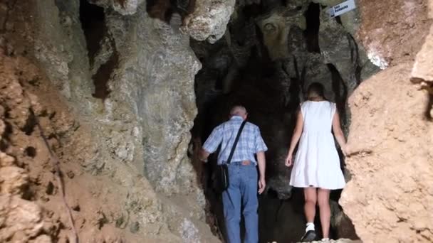 Een oude gids toont toeristen de grot. Extreme rust. — Stockvideo