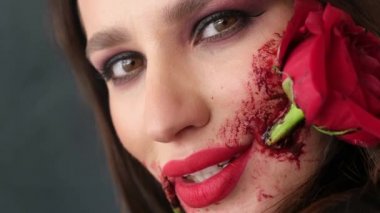 Yüzünde güzel bir sanat eseri olan güzel bir kız, ağzında bir gül çiçeği var.. 