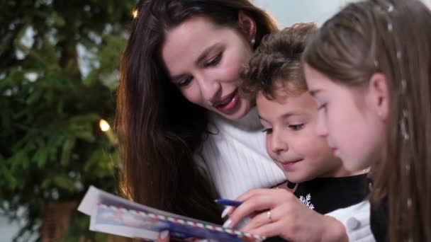 Молодая мама с детьми веселится и пишет письмо Санта-Клаусу. — стоковое видео