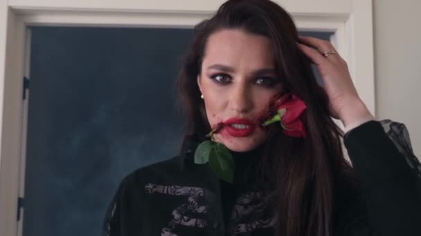 Mooi meisje met een mooi kunst make-up op haar gezicht ze heeft een roos bloem in haar mond. — Stockvideo