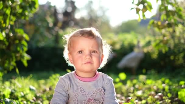 Retrato de un niño que está en la hierba verde en el jardín. Cara feliz — Vídeos de Stock