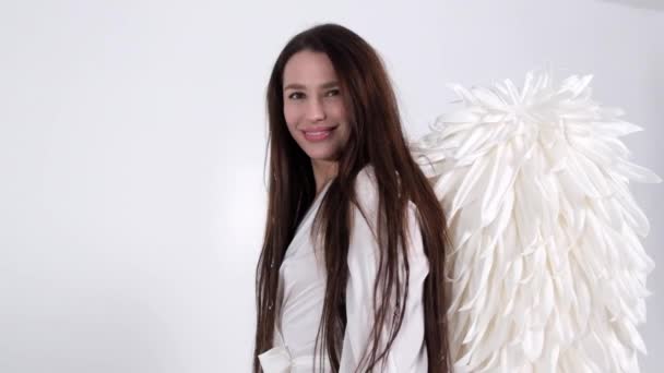 Brunette fille dans une robe blanche avec des ailes d'ange sur un fond blanc dans le studio — Video