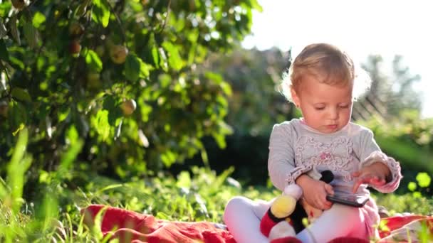 Glad liten flicka som sitter på det gröna gräset. Barnet leker på dagis. Bebis leende — Stockvideo