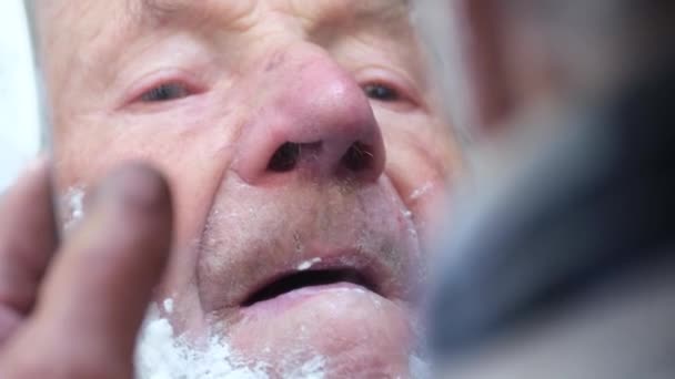 Старий сіроокий старший дід наносить піну обличчям до обличчя для гоління і дивлячись у дзеркало — стокове відео