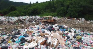 Çöp sahasındaki eski traktör. Kocaman plastik çöp yığını. Doğa için ekolojik felaket. 
