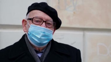 Son sınıf öğrencisi karantina sırasında şehirde bir bankta oturuyor. Dedem koruyucu maskeli. 