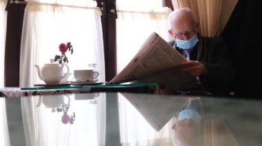 Üzgün bir büyükbabanın portresi, bir kafede oturan basını okuyor.. 