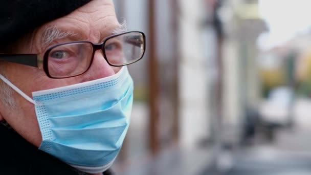 Un pensionista camina por las calles de una ciudad europea durante la cuarentena. Abuelo en una máscara protectora — Vídeos de Stock