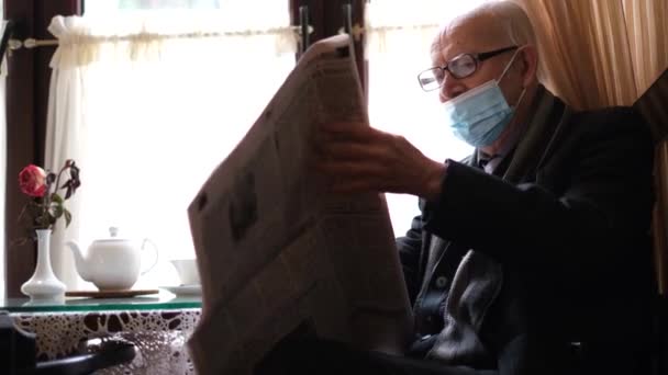 El viejo abuelo lee la prensa mientras está sentado en un café. El pensionista está descansando — Vídeo de stock