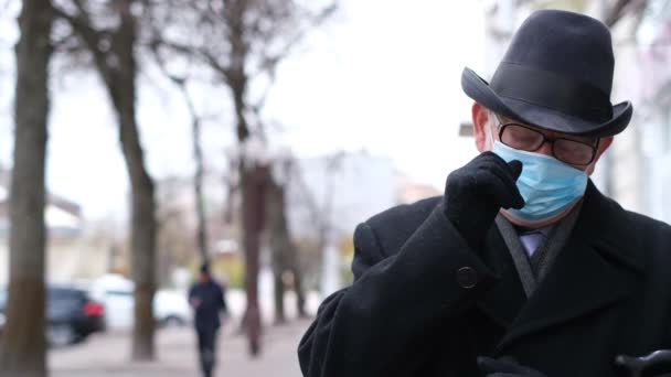Bir emekli karantina sırasında bir Avrupa şehrinin sokaklarında yürür. Dedem koruyucu maskeli. — Stok video