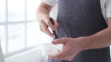 Genç yetenekli ressam büyük beyaz bir tuvale resim yapar, renkli, elle tutulur bir yağlı boya resim yapar.