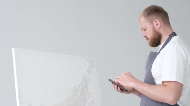 Jovem artista trabalhando na frente de uma tela no estúdio, pintando um quadro, artista moderno feliz — Vídeo de Stock