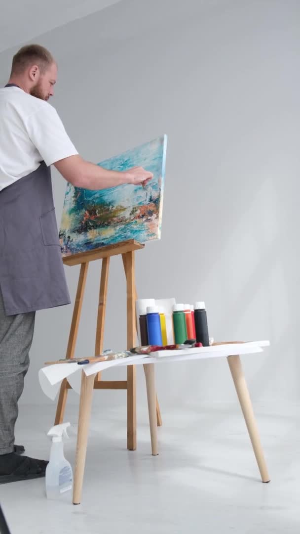 Moderní umělec pracující ve studiu emocionálně maluje na velké bílé plátno štětcem — Stock video