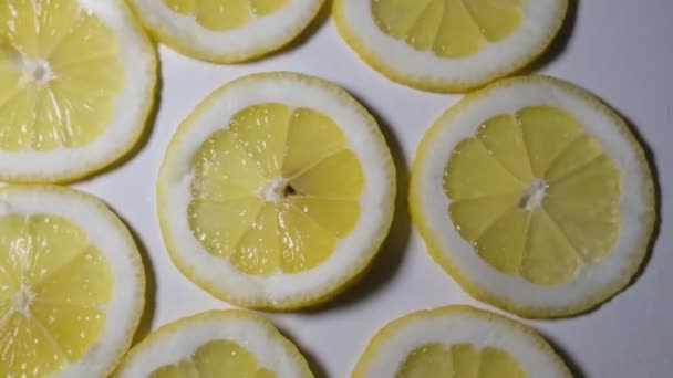 Cortados jugosos limones que yacen aislados sobre un fondo blanco, giran en círculo. — Vídeo de stock