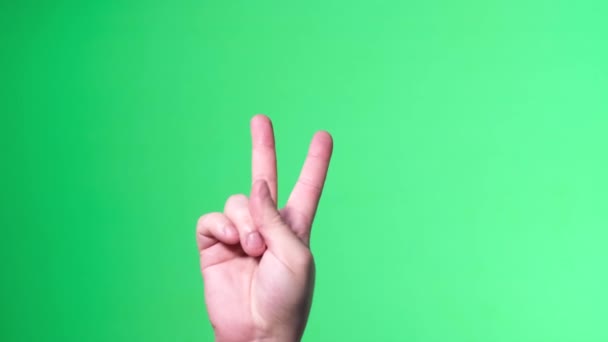 Male hand on green background shows hand sign, victory gesture. — Vídeos de Stock