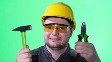 Genç mühendis portresi kameraya bakıyor ve gülümsüyor, elinde aletlerle.