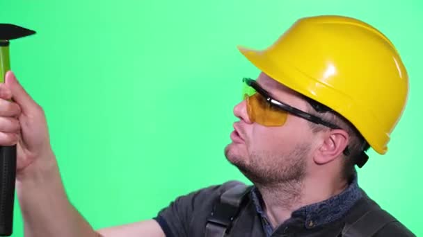 建造者在工作室的彩色键的背景上用锤子工作 — 图库视频影像