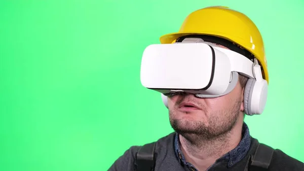Portrait of a male builder in virtual glasses on a green chromakey background. — Zdjęcie stockowe