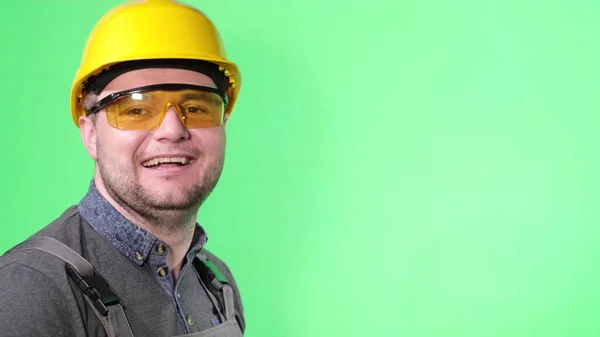 Портрет инженера-рабочего на зеленом фоне, смеющийся показывая большой палец вверх — стоковое фото