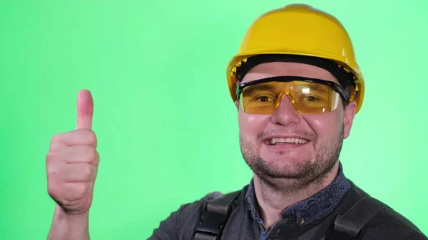 Portret van een mannelijke bouwer op een achtergrond van een chromakey in de studio met een gele helm — Stockfoto