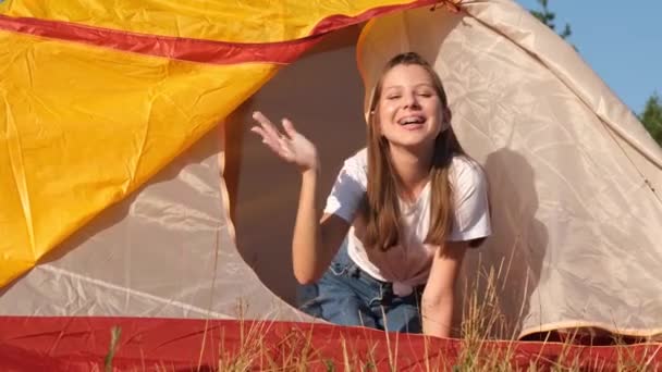 Teenagermädchen schaut aus dem gelben Zelt und zeltet für Kinder im Wald. Kinder entspannen in der Natur — Stockvideo