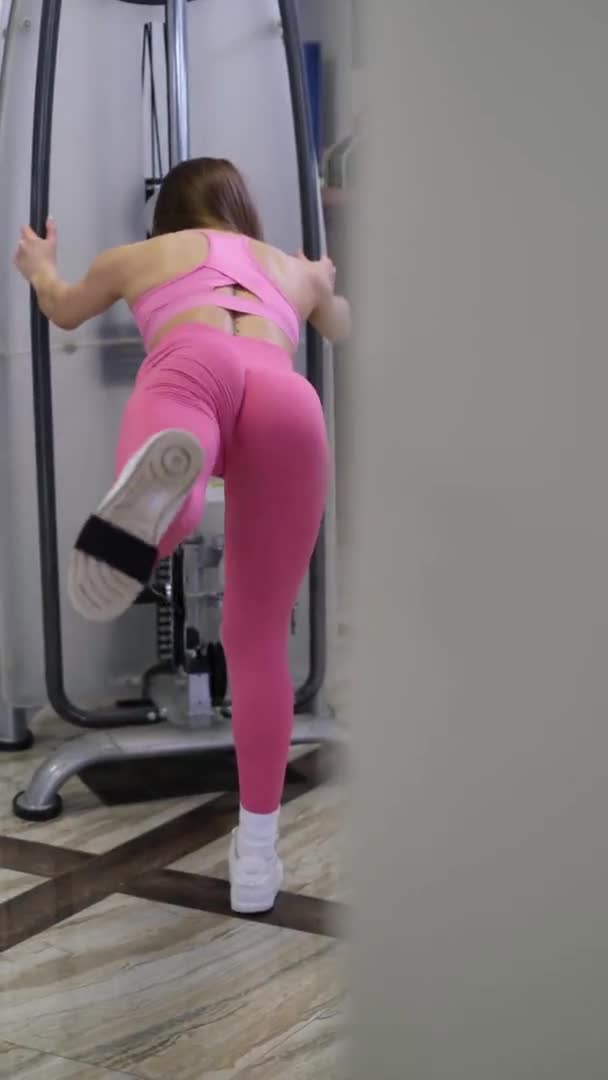 La chica del gimnasio entrena los músculos de las piernas. Elegante cuerpo de entrenamiento de mujer joven — Vídeos de Stock