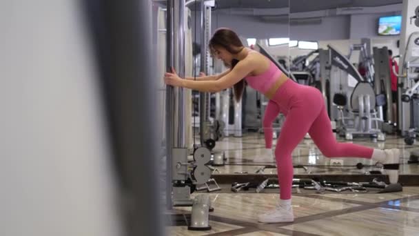 The girl in the gym trains the leg muscles. Stylish young woman training body — Wideo stockowe