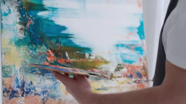 Maschio artista dipinge un quadro con vernici ad olio, artista mentre lavora in studio — Foto Stock