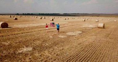 Genç mutlu bir çift kaygısız koşar ve buğday tarlasına atlar. ABD bayrağını tutan