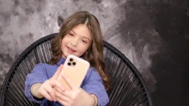 Küçük kız modern telefonuyla fotoğraf çekiyor.