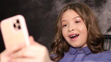 Küçük kız modern telefonuyla fotoğraf çekiyor.