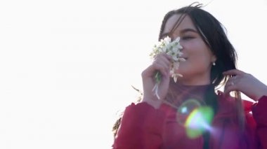 Güzel gülümseyen esmer kız elinde bir buket kardamlası tutuyor ilk bahar çiçekleri.