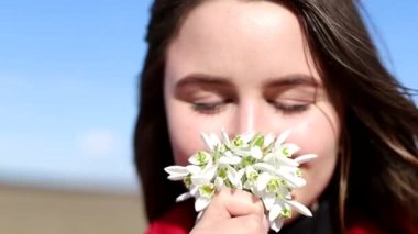 Güzel gülümseyen esmer kız elinde bir buket kardamlası tutuyor ilk bahar çiçekleri.