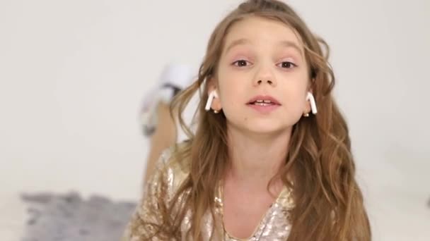 Маленька дівчинка слухає музику з бездротовими навушниками. Щаслива дитина — стокове відео