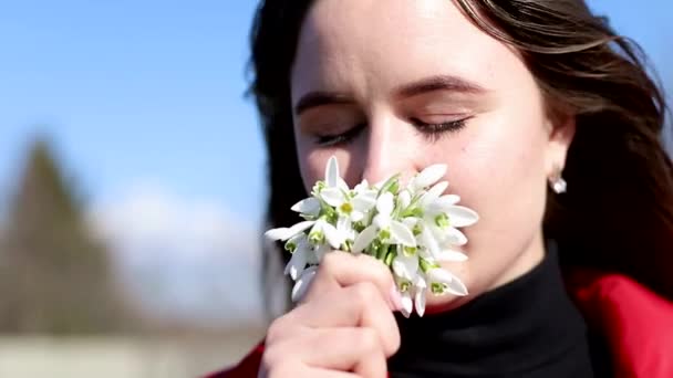 美しい笑顔ブルネット女の子保持花束の雪滴最初の春の花. — ストック動画