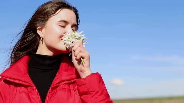 Vacker leende brunett flicka som håller bukett med snödroppar första våren blommor. — Stockvideo