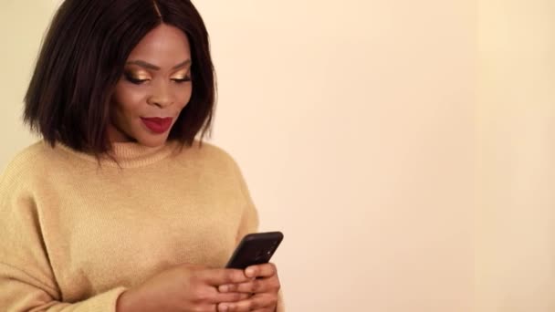 Μια νεαρή Αφρο-Αμερικανίδα χαμογελάει για τον Selfies, ένα κορίτσι χρησιμοποιεί ένα smartphone για κοινωνικά δίκτυα — Αρχείο Βίντεο