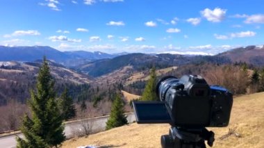 Kamera, ormanın üzerindeki üç ayaklı bir zaman diliminde dağları görüyor..