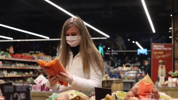 En el supermercado, la rubia en una máscara médica elige productos con descuento — Vídeos de Stock