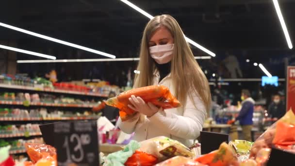 I snabbköpet väljer blondinen i medicinsk mask rabatterade varor. — Stockvideo