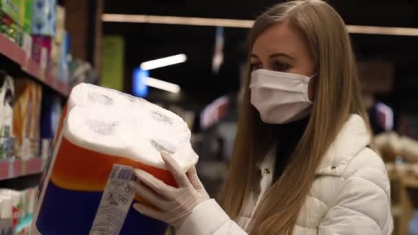 Menina em uma máscara no mercado em um fundo de papel higiênico — Vídeo de Stock